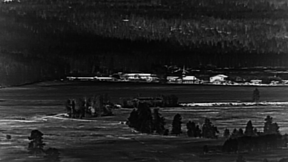 Thermal image of fields and distant buildings.