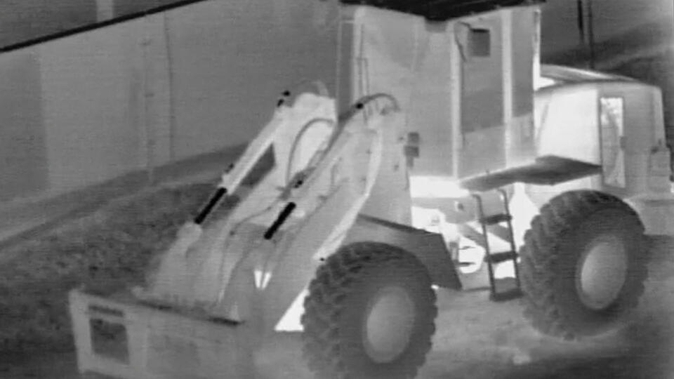 Heavy duty construction equipment at night viewed with thermal imaging.